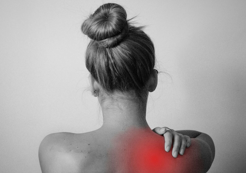 Woman's back with redness on shoulder. She is reaching back to the redness as if in pain.