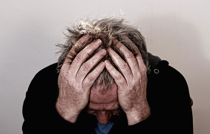 Man sitting with head in his hands, anxious.