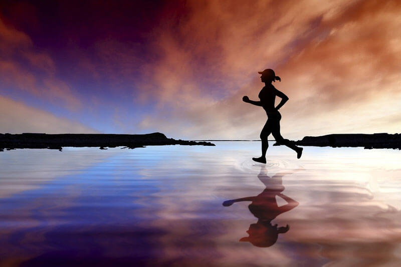 Woman running on beach at sunset.