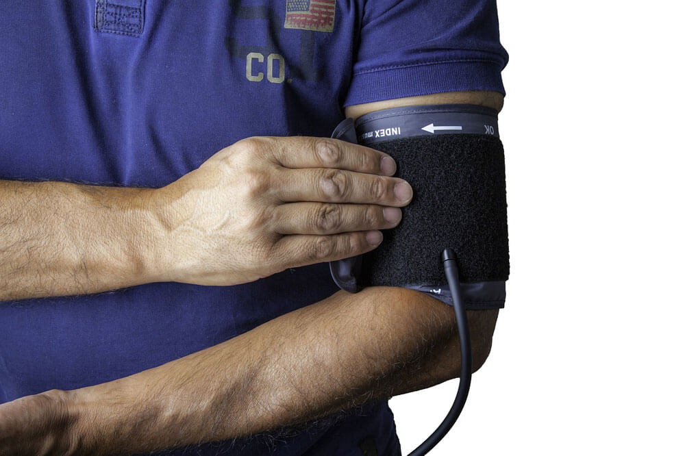 Man's torso dressed in medical scrubs with a blood pressure apparatus around his arm