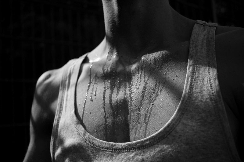 torso of man with white tank top on sweating